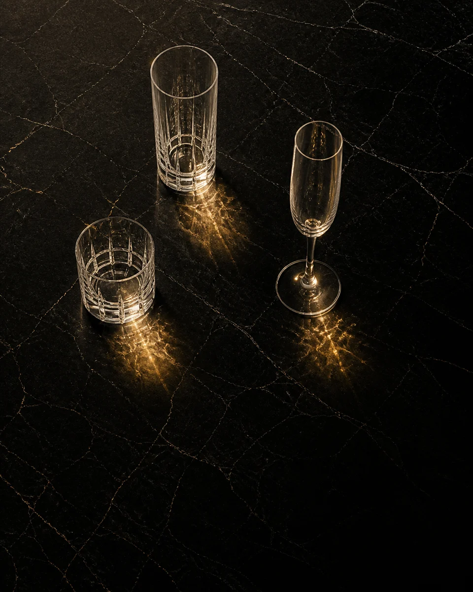 Tres vasos distintos dispuestos en triángulo sobre una mesa de mármol oscuro.